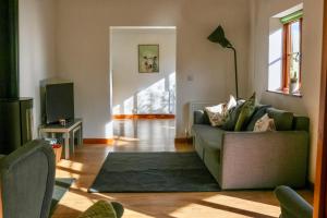 a living room with a green couch and a rug at Tranquil and cosy cottage on the Somerset Levels in Bridgwater