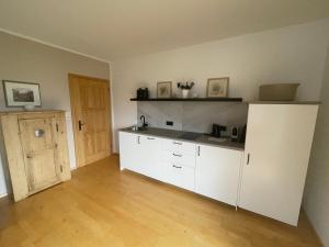 a kitchen with white cabinets and a wooden floor at Ferienwohnung Elisabeth in Altaussee +3 photos