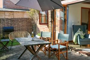 a table and chairs with an umbrella on a patio at Tranquil and cosy cottage on the Somerset Levels in Bridgwater