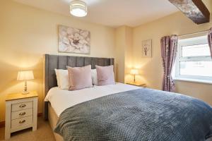 ein Schlafzimmer mit einem Bett und zwei Lampen und einem Fenster in der Unterkunft Host & Stay - Dairy Cottages in Masham