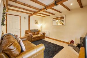 ein Wohnzimmer mit 2 Ledersofas und einem TV in der Unterkunft Host & Stay - Dairy Cottages in Masham