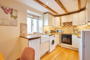 a kitchen with white cabinets and a washer and dryer at Host & Stay - Dairy Cottages in Masham +12 photos