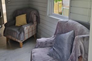 a room with two chairs and a couch and a window at Glamping Hut - Sleeps 2 hot tub & parking in Garthbeibio