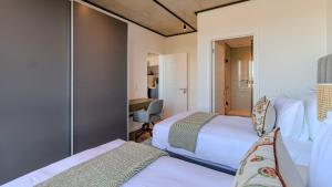 une chambre d'hôtel avec deux lits et un bureau dans l'établissement The Bridgewater Collection 409-Luxury 2 bed Modern Apartment at Century City, au Cap