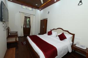 a bedroom with a large bed with red pillows at KSTDC Hotel Mayura Sudarshan ,Ooty in Ooty