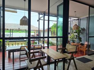 a room with a wooden table and chairs and a large window at D Hostel by the river in Kanchanaburi City