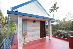 a house with a blue roof and a balcony with a door at Penuel marari homesty in Mararikulam