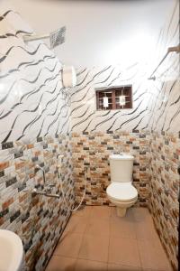a bathroom with a toilet and a brick wall at Penuel marari homesty in Mararikulam