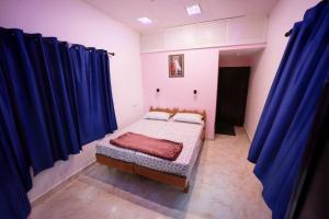 a small bedroom with blue curtains and a bed at Penuel marari homesty in Mararikulam