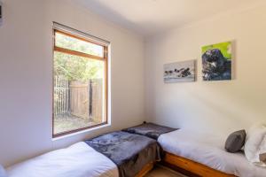zwei Betten in einem Zimmer mit Fenster in der Unterkunft Oyster Cottage in Plettenberg Bay