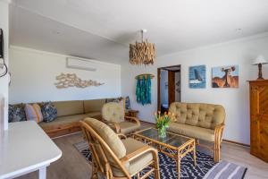 ein Wohnzimmer mit Sofa, Stühlen und einem Tisch in der Unterkunft Oyster Cottage in Plettenberg Bay
