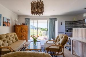 ein Wohnzimmer mit einem Sofa, Stühlen und einem Glastisch in der Unterkunft Oyster Cottage in Plettenberg Bay + 8 Fotos