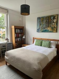 a bedroom with a bed and a book shelf at Large garden-view room, 20 min from Central London, in a stylish period property in Lee, with free parking and a friendly Jack Russell in London