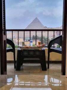 a table and chairs with a view of the pyramid at Roma - pyramids view in Cairo
