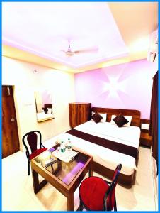 カタックにあるHotel Inn Blue Sagar -Lift & Parking Facilities - Room Service & Restaurant - Garden - free wifi - Boutique Collection and Unique Room Decoration # Best Hotel In Puriのベッドとテーブルと椅子のあるホテルの部屋