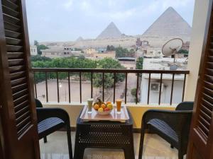 a table with a bowl of fruit on a balcony with the pyramids at Roma - pyramids view in Cairo