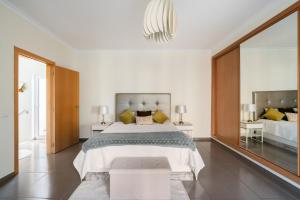 Un dormitorio con una cama grande y un espejo grande. en Homebyvi, en Quarteira