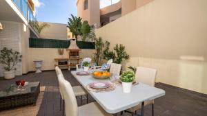 una mesa y sillas blancas en un patio con mesa y sillón en Homebyvi, en Quarteira