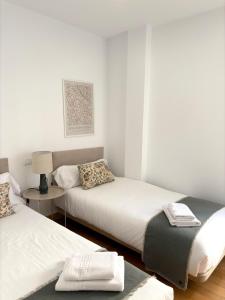 a bedroom with two beds and a table with a lamp at The Zentral Suites & Apartments in Seville