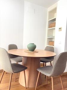 a wooden table with chairs and a vase on top at The Zentral Suites & Apartments in Seville