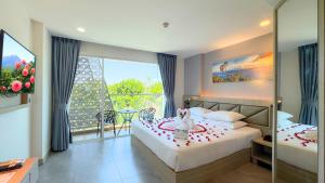 um quarto com duas camas e uma janela grande em Clarian Hotel Beach Patong em Patong Beach