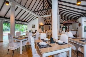 a dining room with white chairs and tables and ceilings at JC's Village in Dambulla