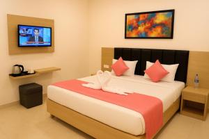 Un dormitorio con una cama con un televisor en la pared. en Hotel Kanha Inn Ayodhya, en Ayodhya