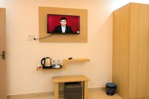Un televisor en una pared con una foto de un hombre. en Hotel Kanha Inn Ayodhya, en Ayodhya
