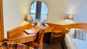a room with a desk with a phone and a bed at Hotel Orion in Budapest