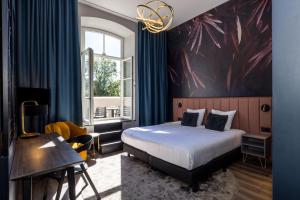 een slaapkamer met een bed, een bureau en een raam bij MERICI Hotel Sittard in Sittard