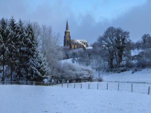 a church in a snow covered field with a building at MERICI Hotel Sittard in Sittard