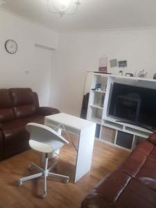 a living room with a couch and a table and a television at Extra king size room spacious in Woolwich