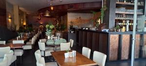 a restaurant with tables and white chairs and a bar at Hotel Montagna Delmondo in Valkenburg +33 photos