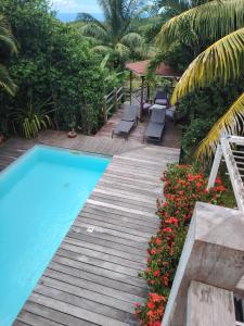 a swimming pool with a wooden walkway and some flowers at Charmant T3 climatisé Piscine privée in Le Diamant
