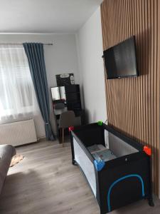 a room with a crib and a tv on a wall at Apartman Relax in Slavonski Brod