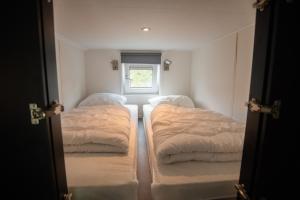 two beds in a small room with a window at De Bijsselse Enk, Noors chalet 15 in Nunspeet