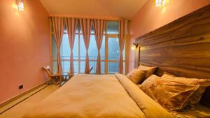 a bedroom with a large bed with a large window at Athiti Kunj Eco Adventure Retreat in Mukteswar