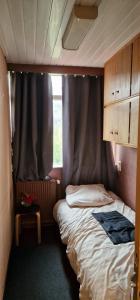 a small bedroom with a bed and a window at Knusse kamer om te kunnen overnachten in Rotterdam