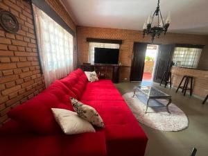 un canapé rouge dans un salon avec un mur de briques dans l'établissement Chácara Vovô João, à São Paulo