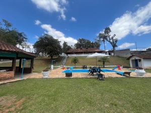 une piscine avec un parasol dans un jardin dans l'établissement Chácara Vovô João, à São Paulo