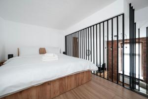 Un dormitorio con una cama blanca y un balcón. en Piotrkowska Luxury Studio with Mezzanine by BookingHost, en Łódź