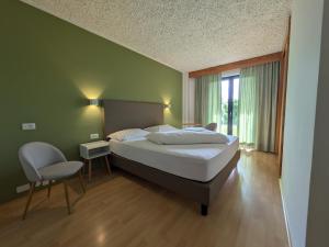 a bedroom with a bed and a chair and a window at Garni Saltneregg Ferienwohnungen in Caldaro