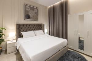 a bedroom with a large white bed and a window at A beautiful one BR apartment with a living room in Al Madinah