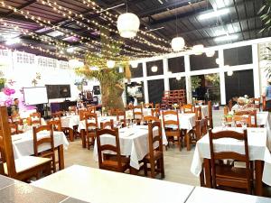 a restaurant with white tables and chairs and a stage at Hotel la fuente j.n in La Macarena