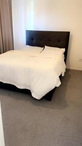 a bed with white sheets and a black headboard at Home in Colchester in Colchester