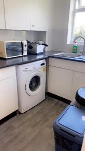 a kitchen with a washing machine and a microwave at Home in Colchester in Colchester
