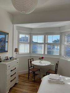 Schlafzimmer mit einem Tisch, Stühlen und Fenstern in der Unterkunft 7 Goathill Crescent in Stornoway