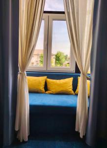 a window seat with yellow pillows and curtains at B & B Drava in Koprivnica