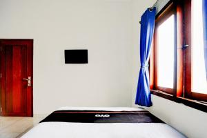 a bedroom with a bed and a window with blue curtains at OYO 94818 Sabina House Syariah in Blitar