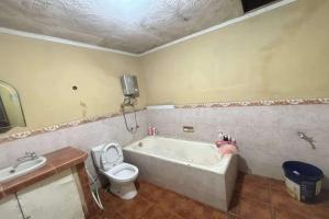 a bathroom with a tub and a toilet and a sink at OYO 94841 Alodia Homestay Family in Kejajar +17 photos